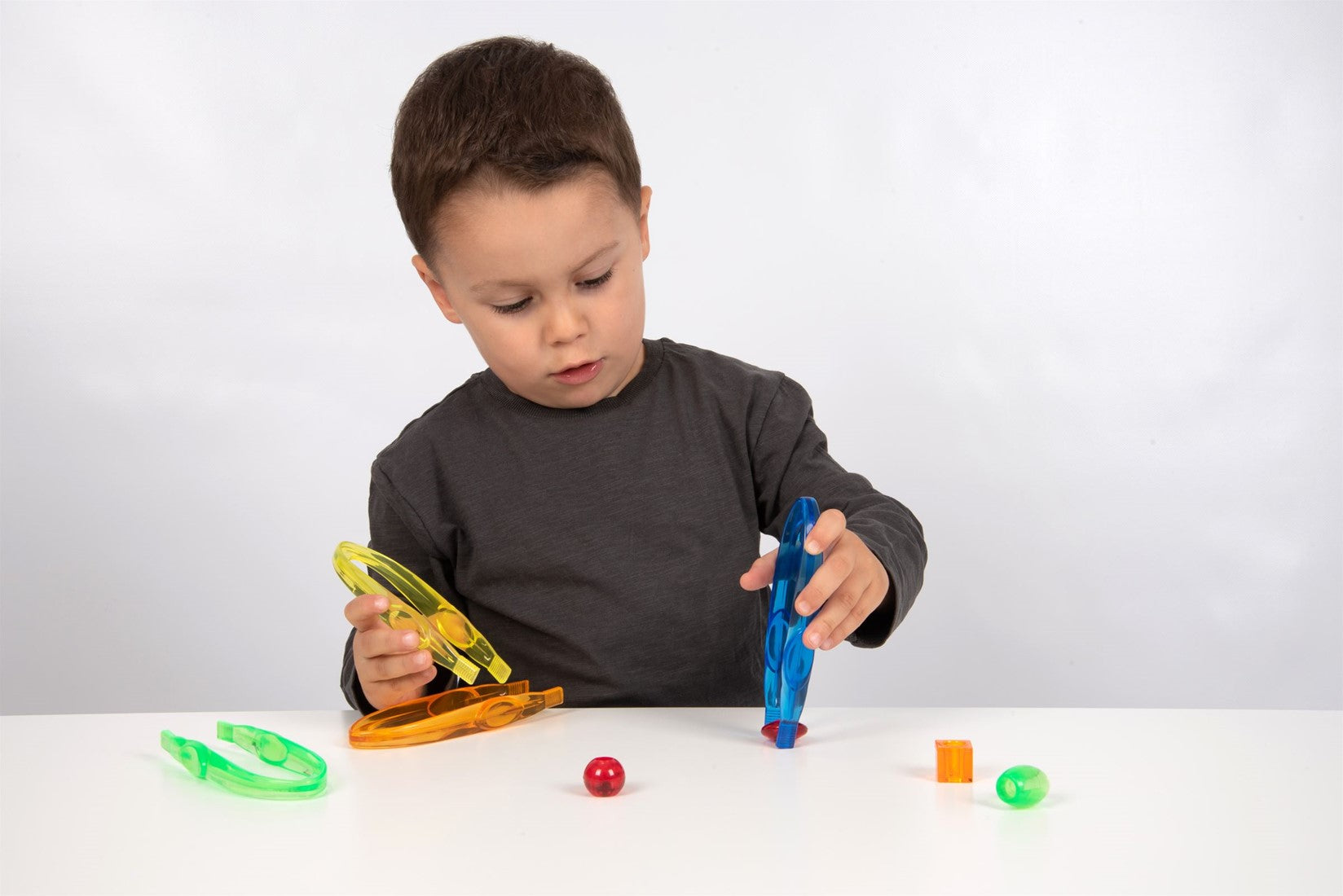 Kind oefent grijpen met pincet tijdens spel